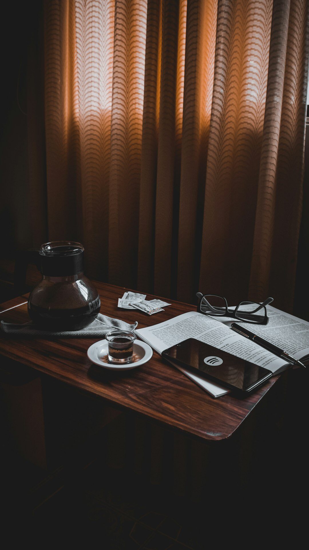 Old wooden writing desk with typewriter, notebook and coffee cup lit by lamp at night