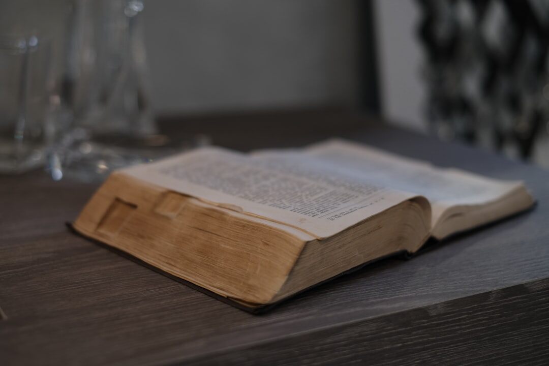 Open old hardcover book with yellowed pages resting on a wooden table with a magnifying glass