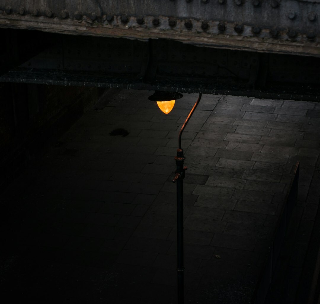 Vintage wrought iron street lamp glowing at night on an empty cobblestone street