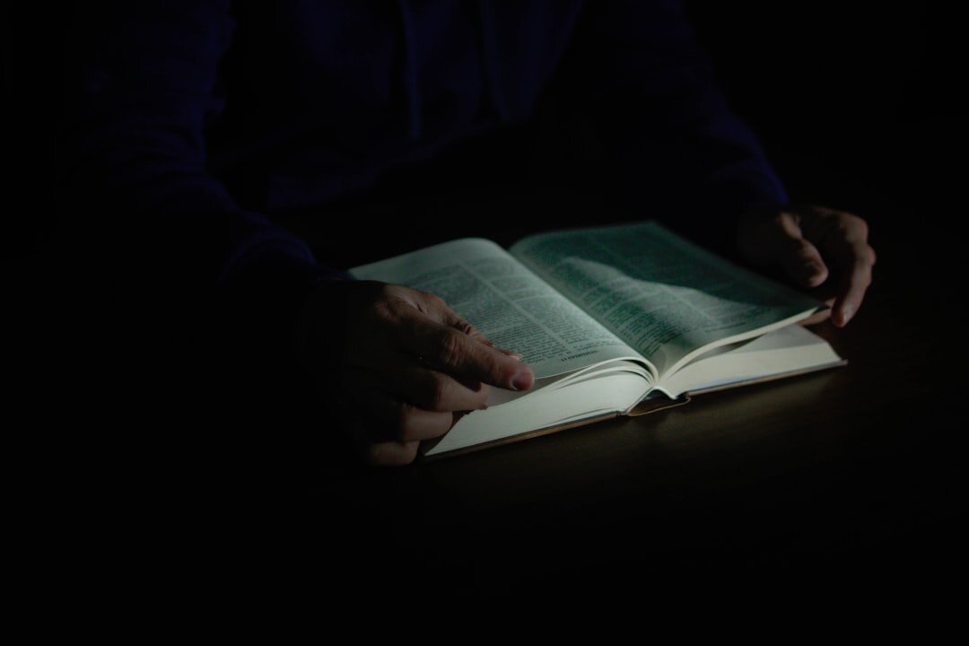 person reading mystery book in dim light
